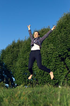 Excited businesswoman jumping in park