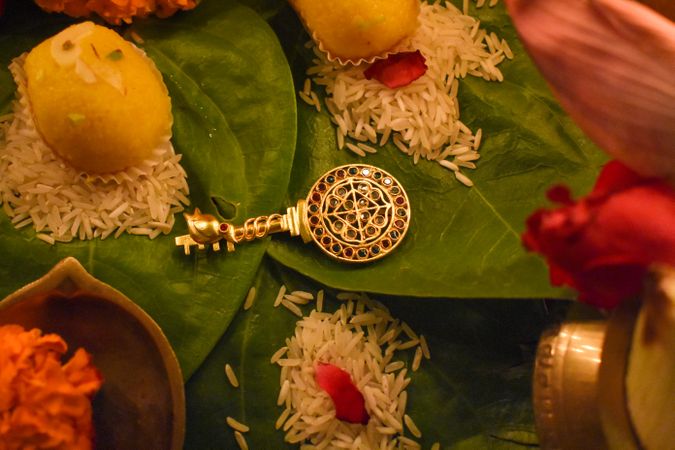 Silver key with mandala head beside yellow ladoo
