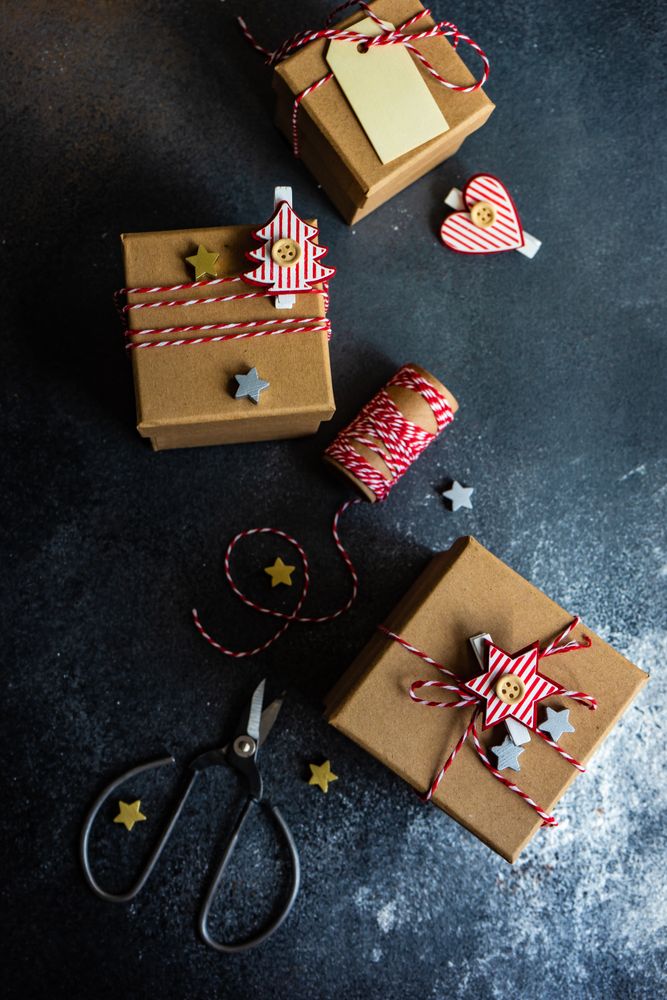 Top view of three brown Christmas presents with decorations, scissors and string