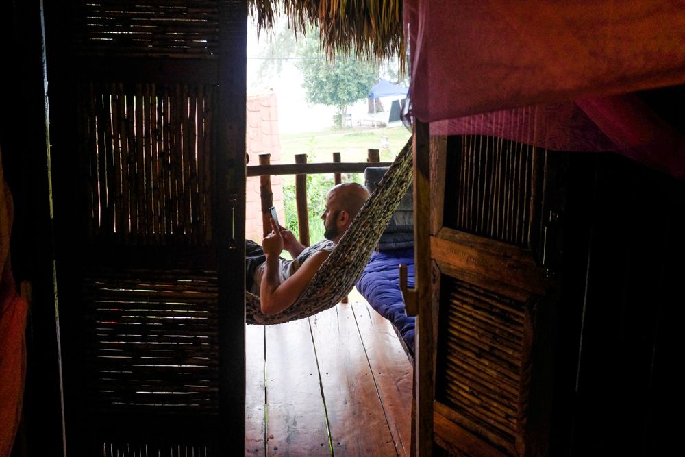 Man resting in hammock on mobile device