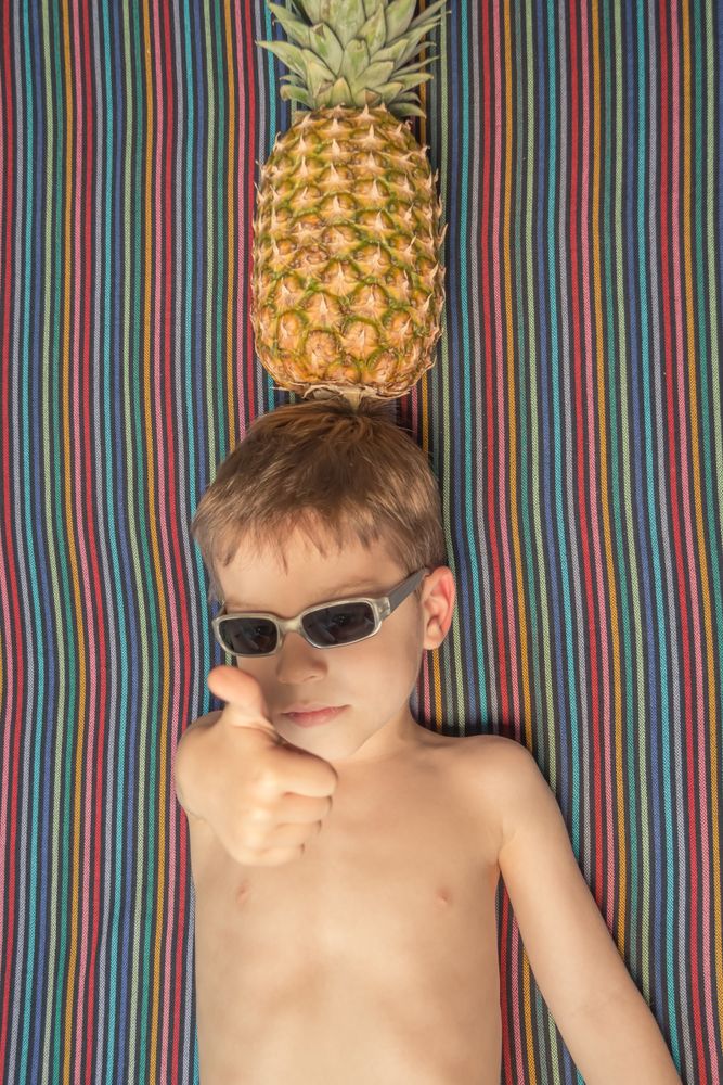 Happy child with sunglasses and pineapple in head