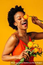 Playful Black woman playing with ranunculus flowers 48qrXb
