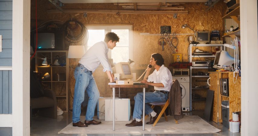 Male Stock Traders Working In Retro Garage, Using Old Desktop Computer With Candlestick Chart