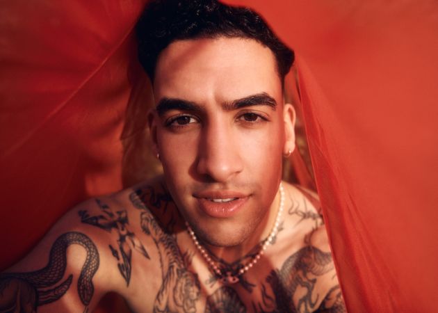 Tattooed male under red sheet