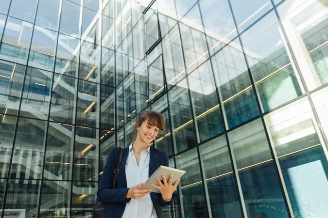 Positive businesswoman using tablet on street