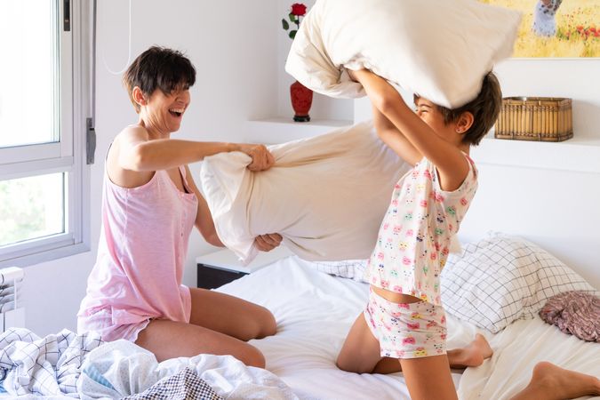 Mother smiling with her daughter having a pillow fight