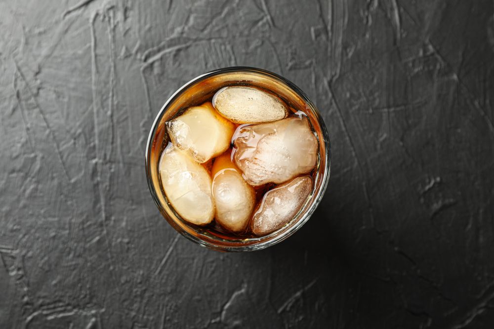 Glass of cold cola on cement background