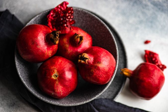 Dark bowl full of fresh whole pomegranates