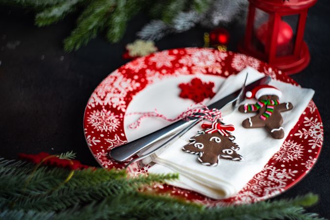 Holiday table setting on red plates with gingerbread decorations