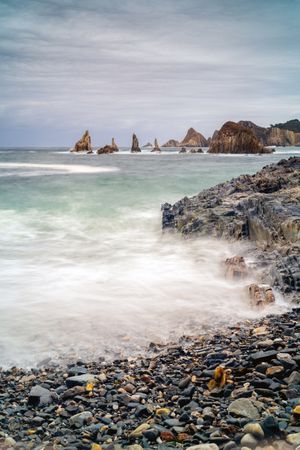 Rocky peaks protrude from water in cloudy day
