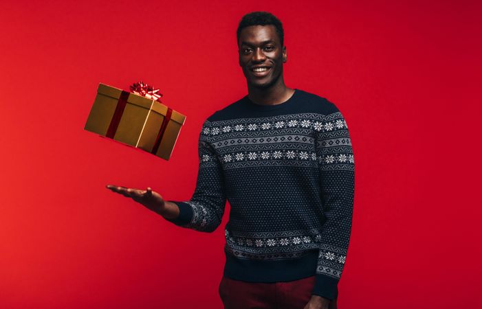 Portrait of young black man tossing up a gift