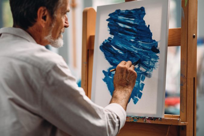 Man painting with blue paint on canvas