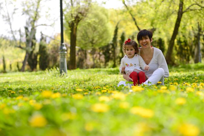 Smiling mother sitting with daughter in park