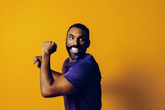 Happy Black man in yellow studio dancing with his head forward, copy space