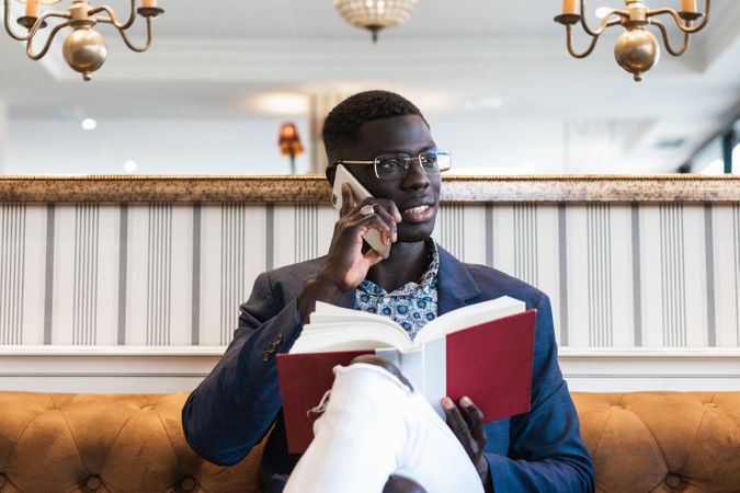 Stylish Black businessman speaking on smartphone on sofa