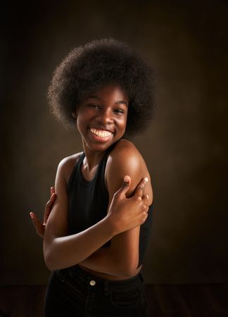 young Black woman with afro hairstyle dancing with arms crossed