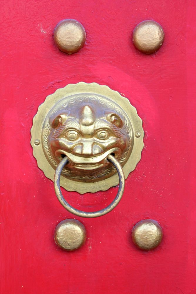 Gollden head of lion in Asian style on red wooden texture. Head of Asian lion on red door.