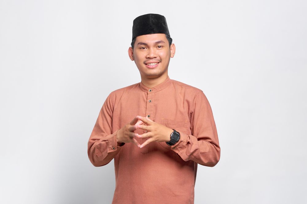 Calm Muslim man in kufi head wear with his fingers together