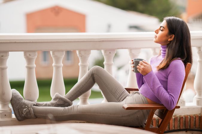 Woman relaxing on outdoor patio with warm beverage