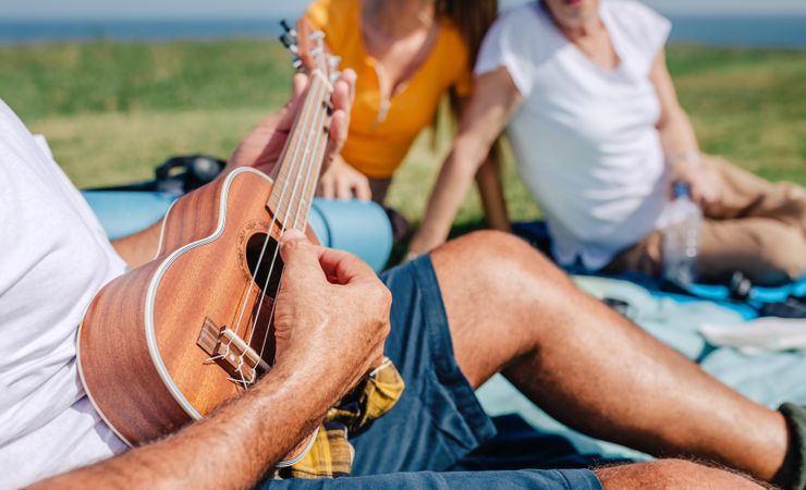 Close up of man playing ukulele on family picnic