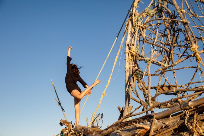 Young woman with upped leg on decorative wooden ship near water on shore