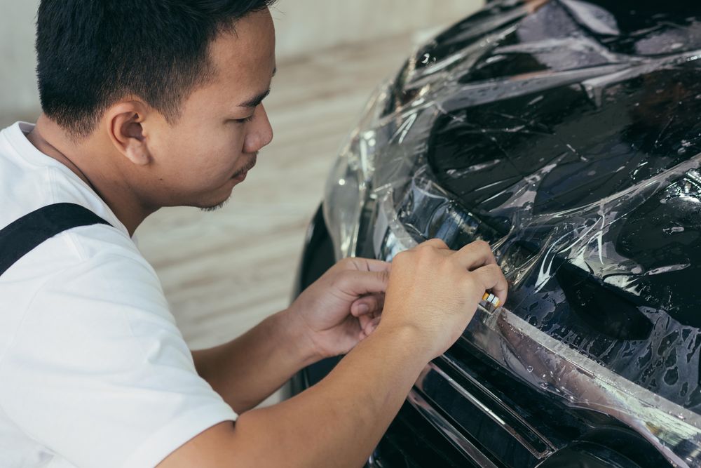 Man smoothing car wrap to front of vehicle