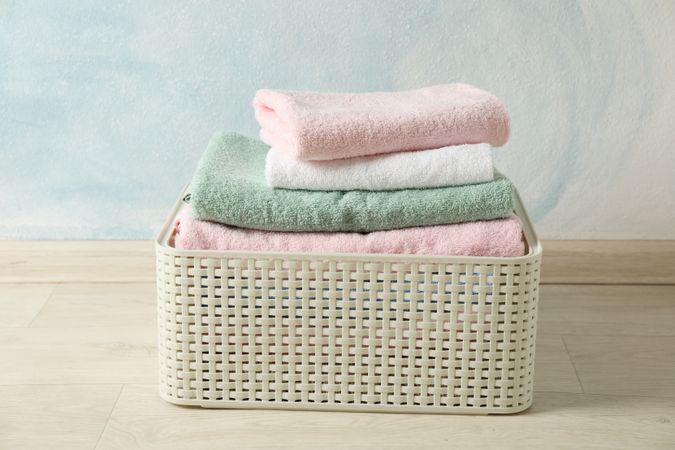 Basket with clean laundry on textured floor, space for text