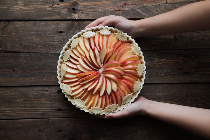 unrecognizable woman showing a tasty apple pie on a wooden table