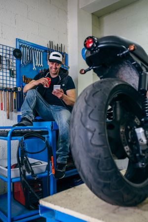 Motorcycles mechanic resting having a beer