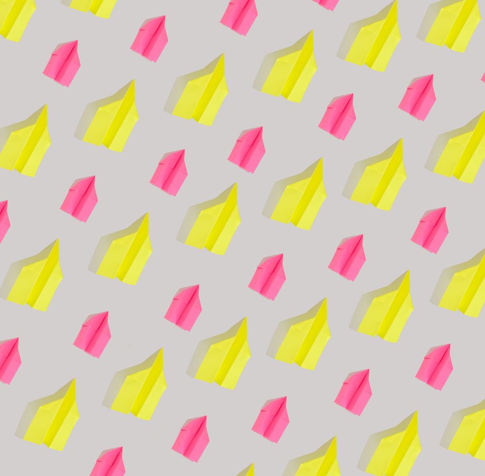 Flat lay of colorful paper airplanes in a pattern