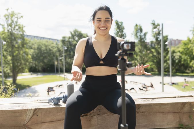 A young woman records herself on video, to explain to her followers, how to perform an exercise and sport workout