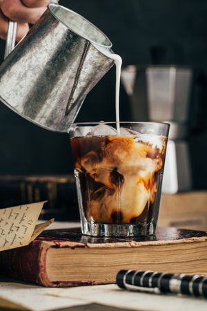 Pouring milk in a cold espresso coffee glass