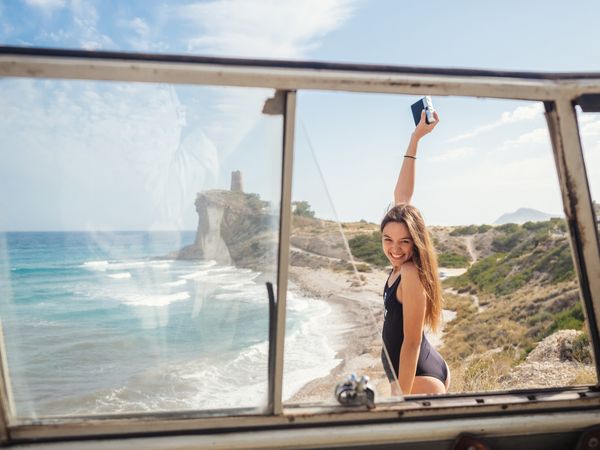Woman taking photo at rocky coast