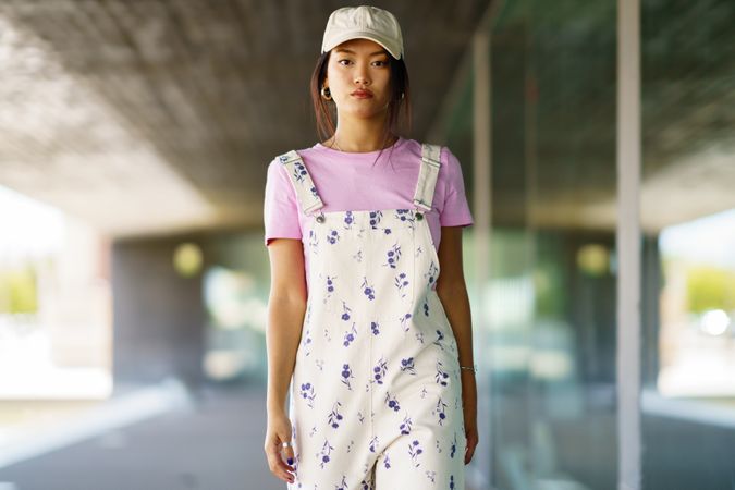 Woman in floral overalls walking on street outside