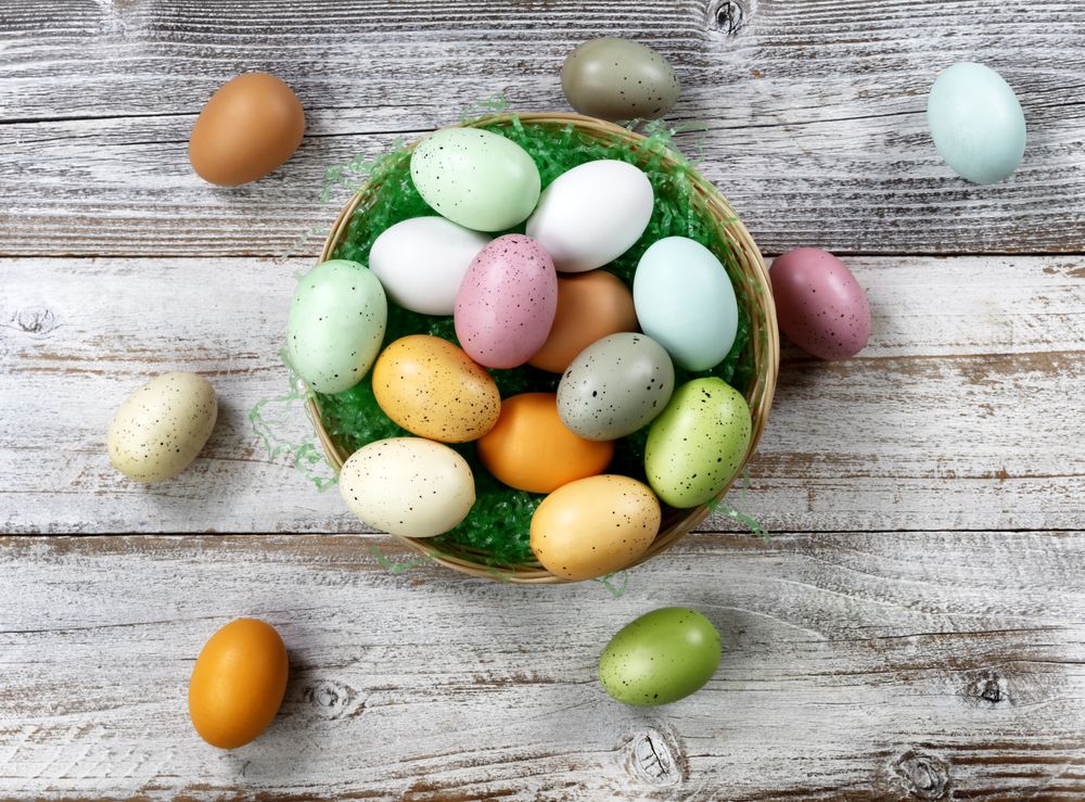 Happy Easter concept with basket filled of colorful eggs on weathered wood