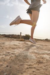 Unrecognizable sportswoman running on sand