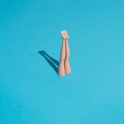 Doll legs sticking upright from blue background with shadow