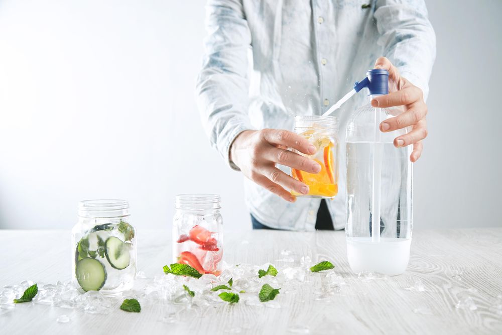 Man filling mason jar with water to make flavored drink