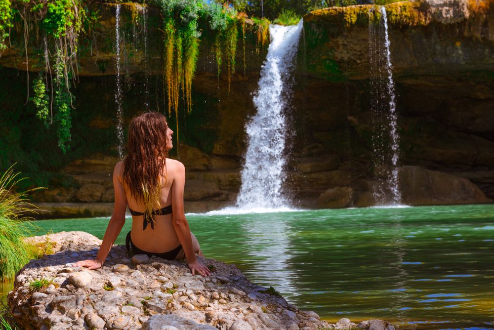 Young female relaxing near waterfall