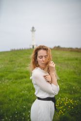 Tender woman in green field with lighthouse