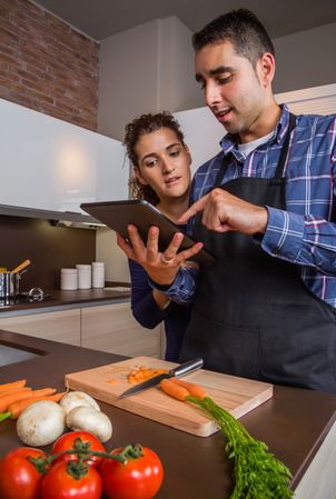 Couple checking digital tablet above cutting board