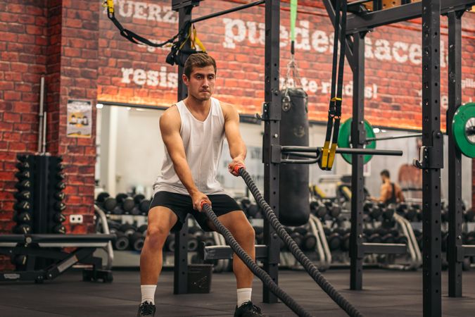 man athlete working out with the ropes in a gym