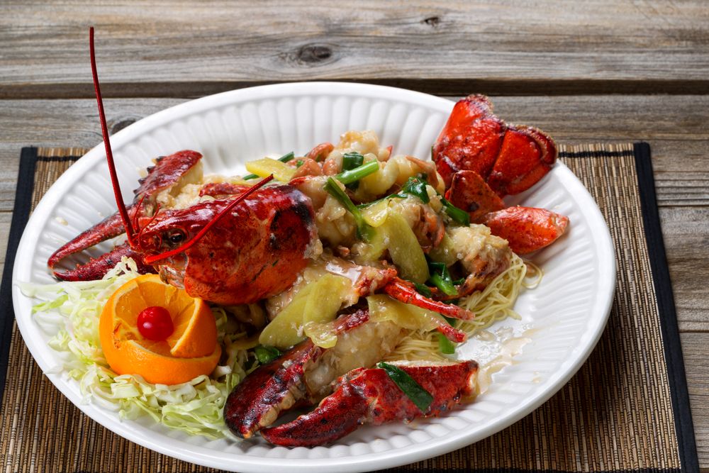 Steamed whole Maine lobster and garnishes on serving plate ready to eat