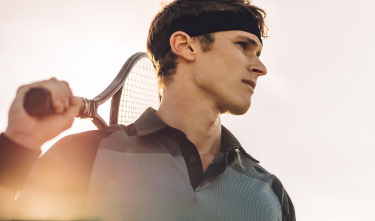 Male tennis player with racket looking away