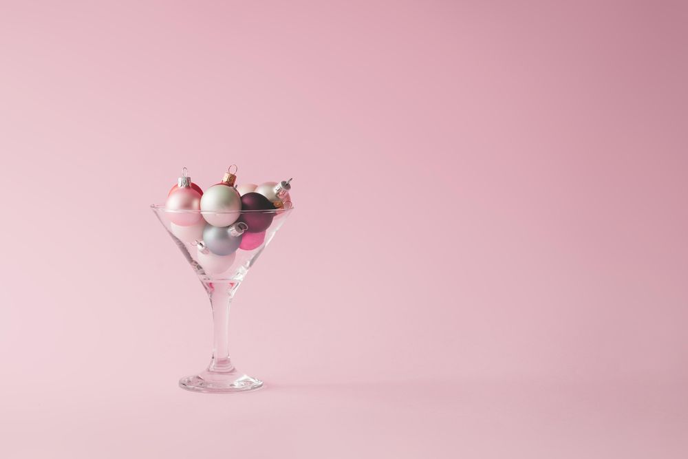 Christmas tree decoration in martini glass on pastel pink background with creative copy space