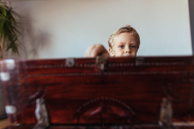 Face of little boy behind old trunk