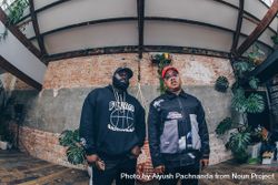 Fisheye wide angle up shot of two Black men standing against industrial exposed brick wall 5wXZZ4