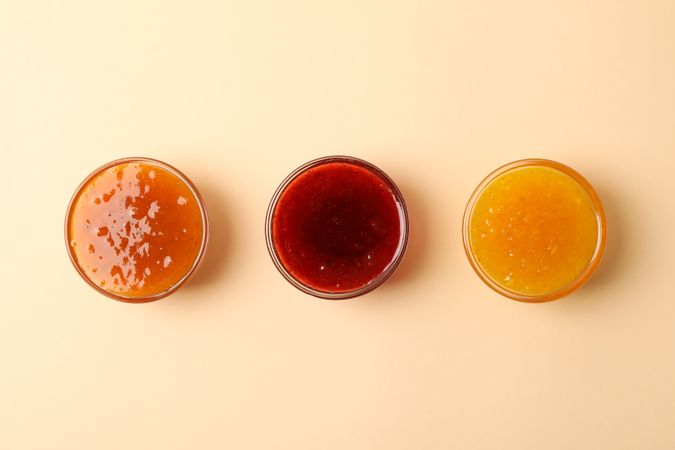 Bowls with jam on beige background, top view