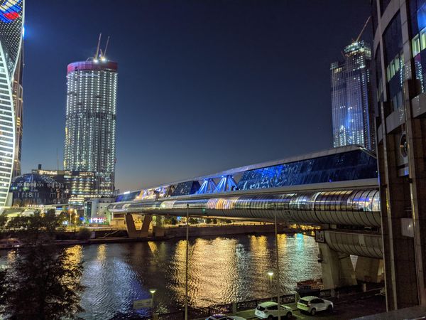Moskva river flowing by shorelines of skyscrapers of Moscow, Russia at night