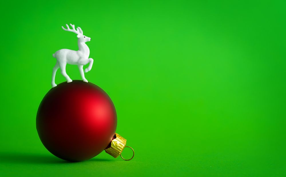 Red bauble decoration on green background with reindeer